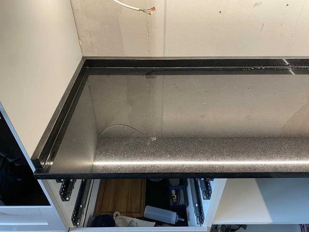 Polerad Nero Assoluto granitbänkskiva längs köksväggen, fotad under montering i Alingsås.
