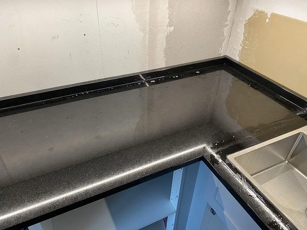 Polerad Nero Assoluto granitbänkskiva i hörnet av köket med underlimmad rostfri diskho i Alingsås.