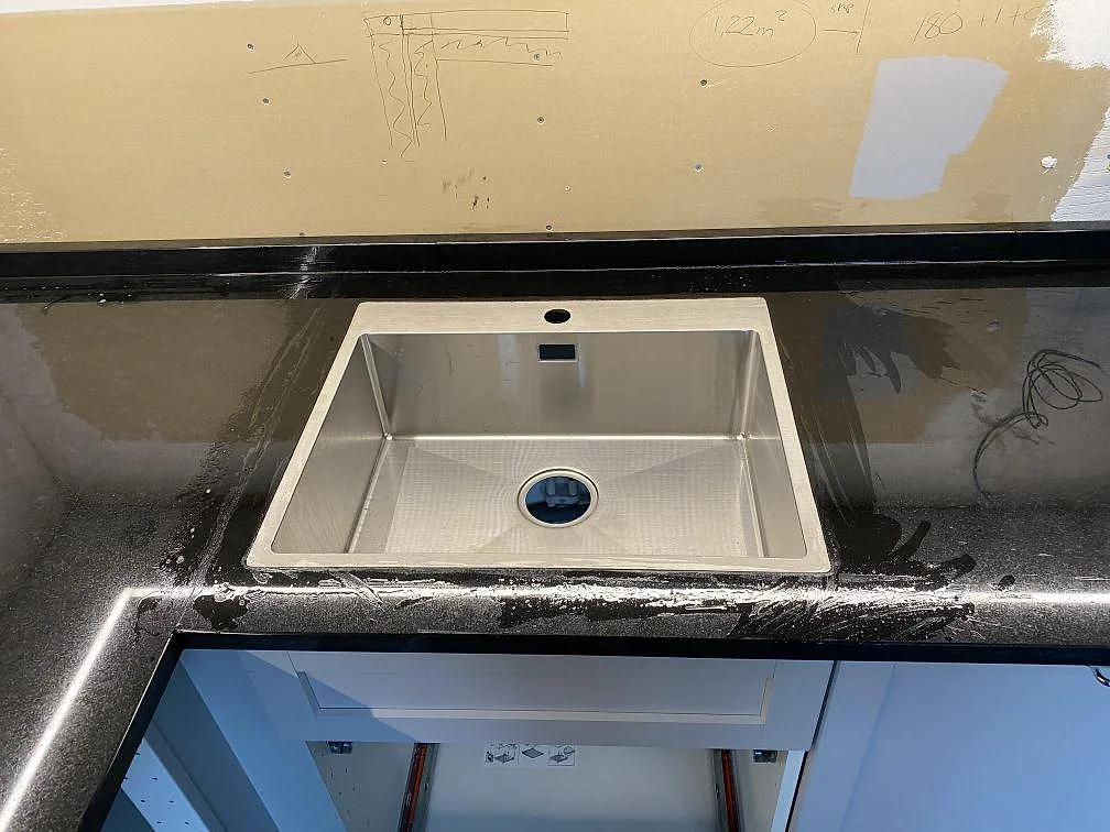 Underlimmad rostfri diskho i en polerad Nero Assoluto granitbänkskiva i ett kök i Alingsås.