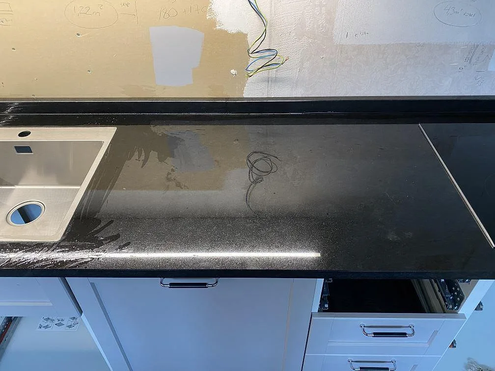 Svart Nero Assoluto bänkskiva med underlimmad rostfri diskho och uppvikt stänkkant i ett kök i Alingsås.