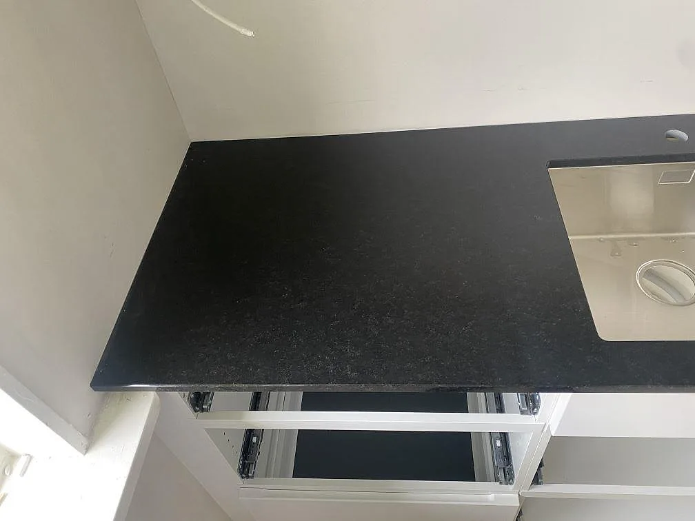 Detalj av matt Nero Assoluto bänkskiva i granit med rostfri diskho och mörk stenyta i Båstad.