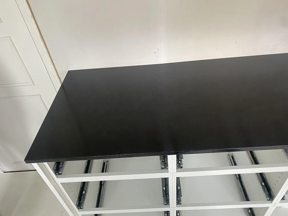 Rak köksbänkskiva i matt Nero Assoluto granit på vita stommar under montering i Båstad.