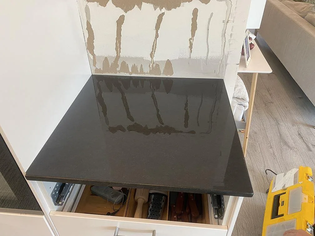 Sidoyta i polerad Nero Assoluto granit på vita köksstommar under köksmontering i Båstad.