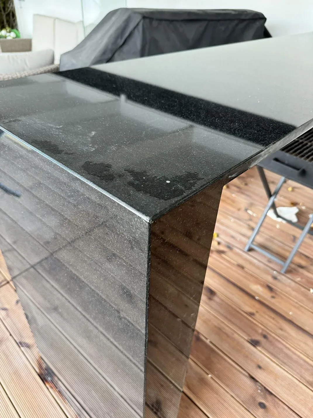 Detalj av hörn och lodrät sida i polerad Nero Assoluto granit på en terrassbänk under montering i Bara.