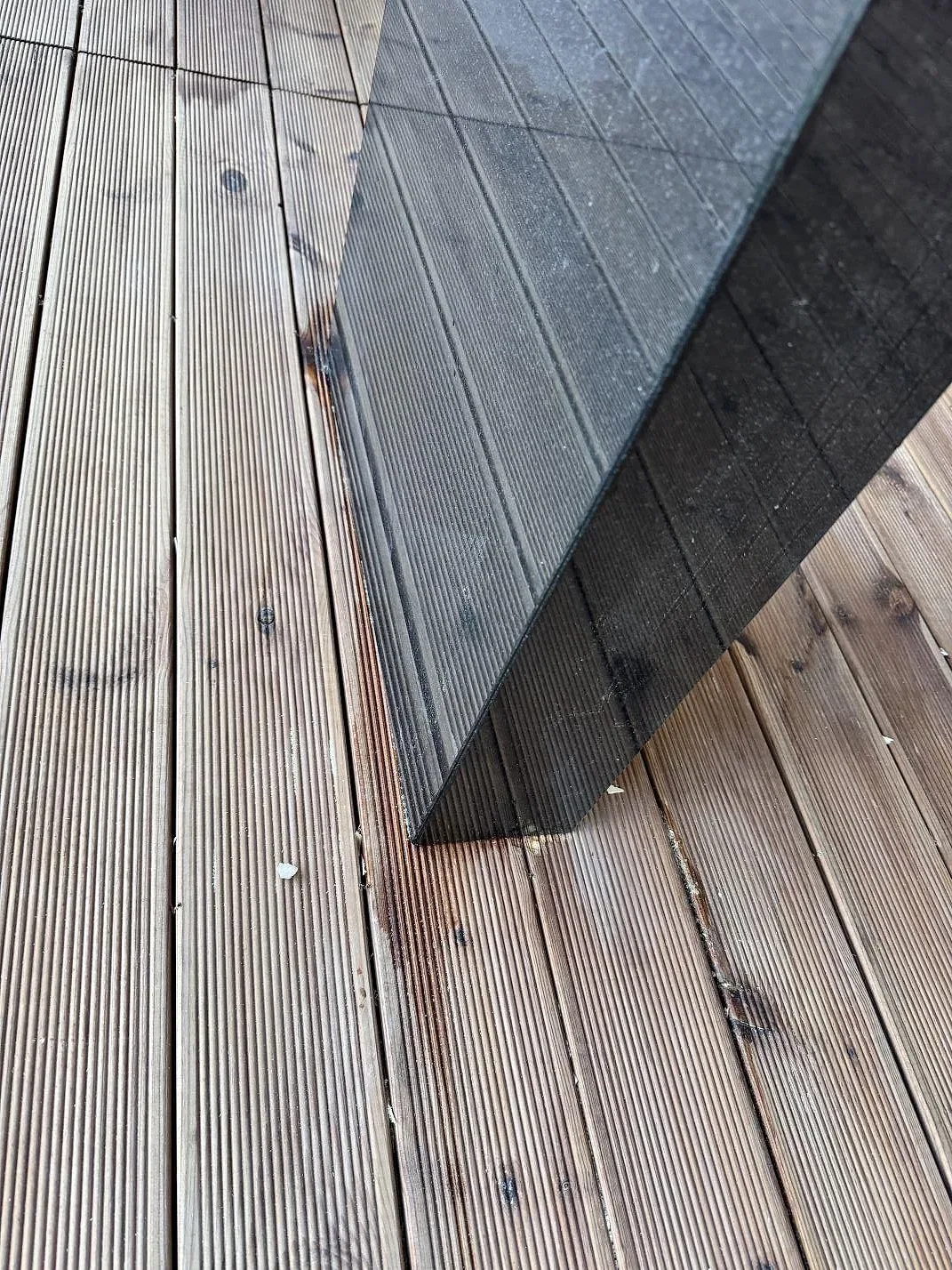 Detalj av lång kant i polerad Nero Assoluto granit där den svarta stenen möter trätrallen i Bara.