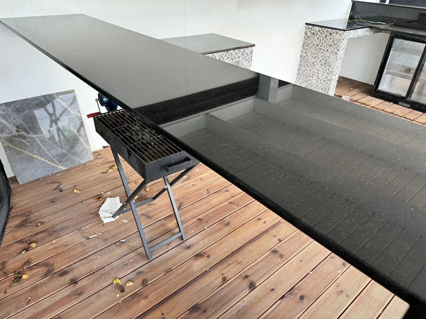 Polerad Nero Assoluto granit på en lång terrassbänk med blank svart yta och grill intill i Bara.