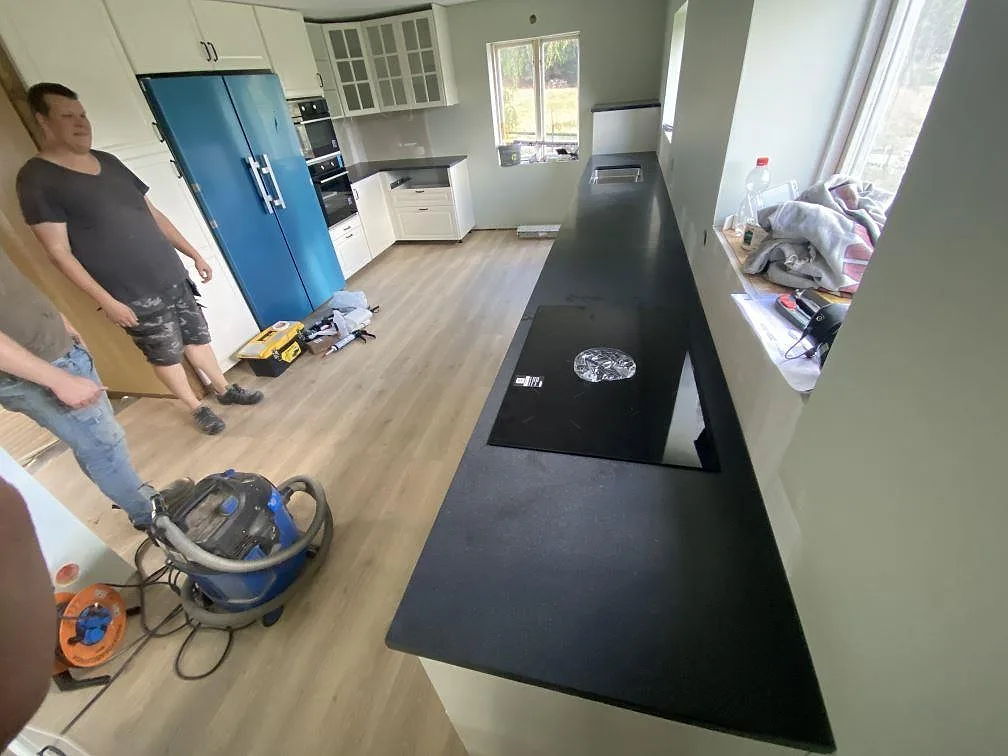 Matt svart Nero Assoluto granitbänk med infälld induktionshäll, eye-level vy i ett kök i Bjärnum.