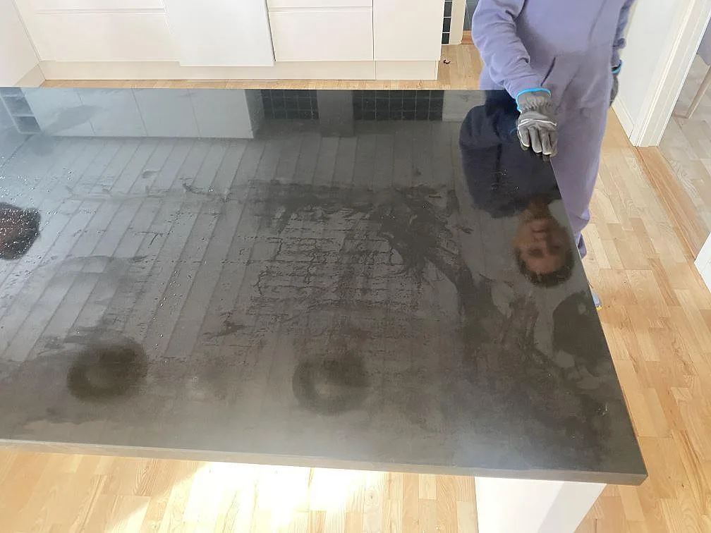 Närbild av polerad Nero Assoluto granit på en köksö i Bjärred, med blank svart yta och reflektioner.