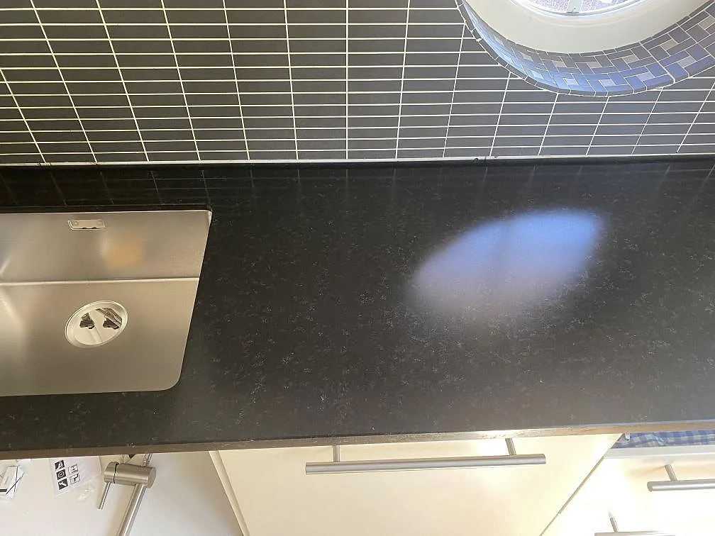 Närbild på den matta svarta Nero Assoluto-bänkskivan med underlimmad rostfri diskho och separat blandarhål i stenen i ett kök i Bohus Björkö.