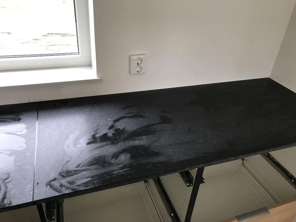 Bänkskiva i Nero Assoluto, matt svart granit, längs väggen vid fönstret under montering i ett kök i Bunkeflostrand.