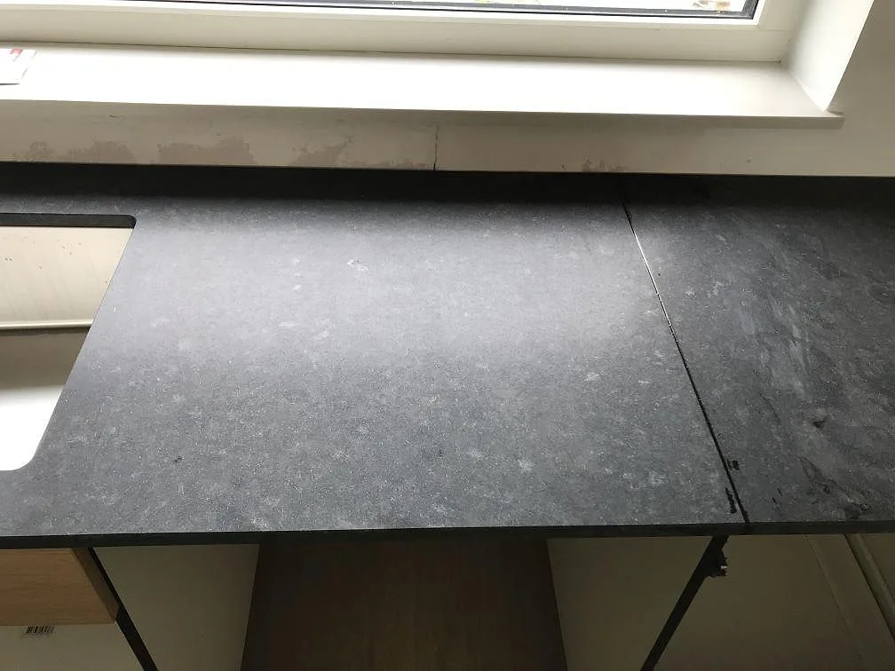 Köksbänkskiva i matt svart granit Nero Assoluto med underlimmad diskho vid fönstret i ett kök i Bunkeflostrand.