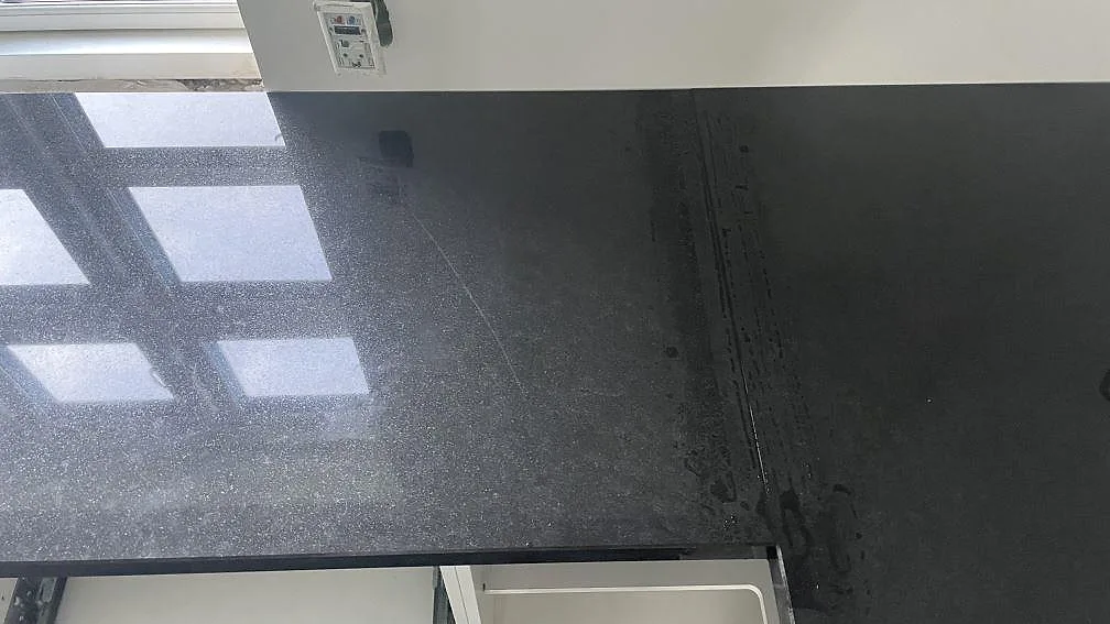 Detalj av speglande polerad Nero Assoluto granit med fönsterreflexer i Christiansfeld.