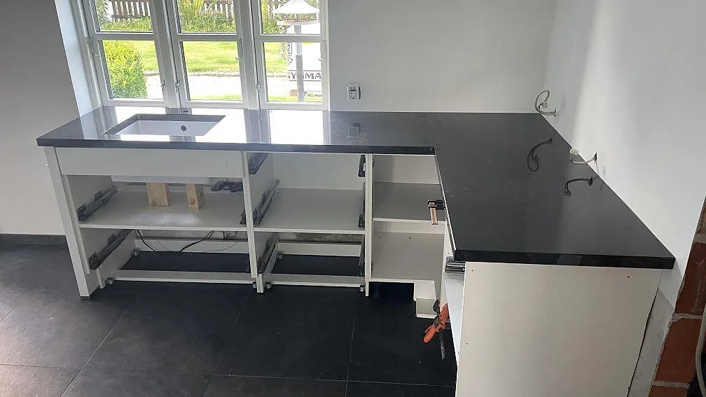 Köksbänkskiva i 40 mm polerad Nero Assoluto granit i ett kök under montering i Christiansfeld.