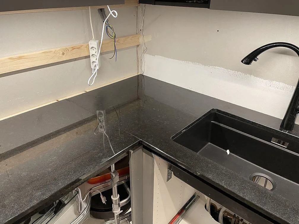 Polerad Nero Assoluto granit runt svart Blanco Silgranit-diskho och svart blandare i köket i Dalby.