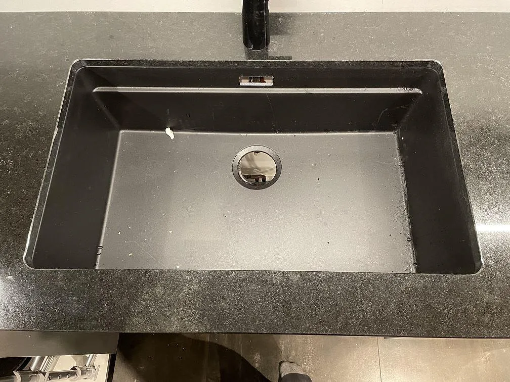 Köksö och bänkytor i polerad Nero Assoluto granit, 20 mm, på vita stommar i ett kök i Dalby.