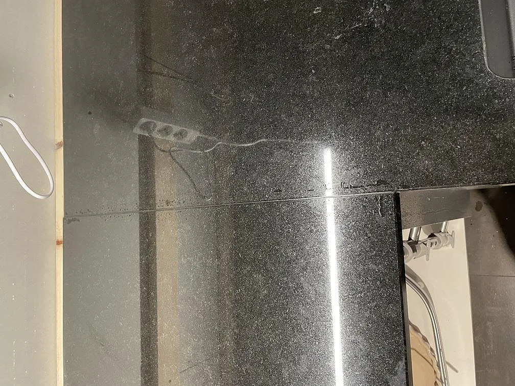 Detalj av polerad Nero Assoluto granit med hörnpassning och ljusreflexer på bänkskivan i Dalby.