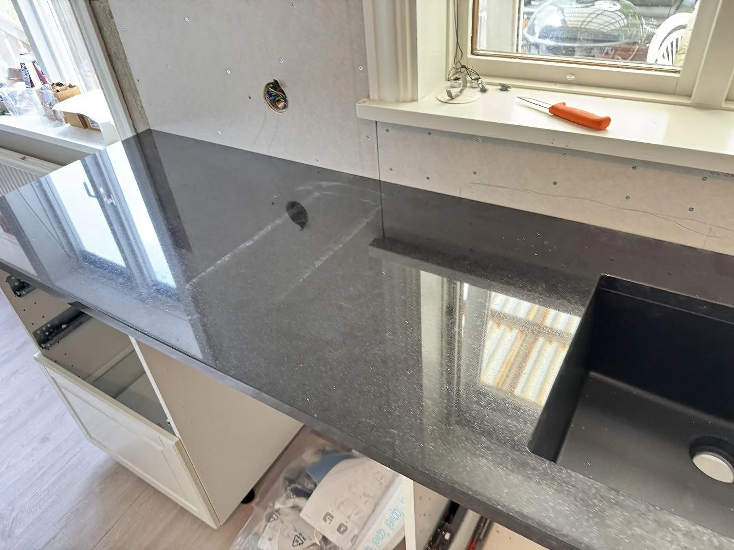 Köksbänkskiva i polerad Nero Assoluto granit med mörk diskho och reflekterande yta i ett kök i Dalsjöfors.