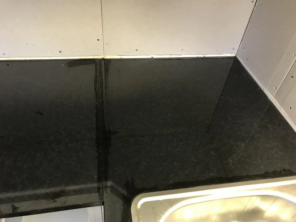 Svart granitbänkskiva i Nero Assoluto med uppvikt stänkkant mot vägg i ett kök i Falköping.