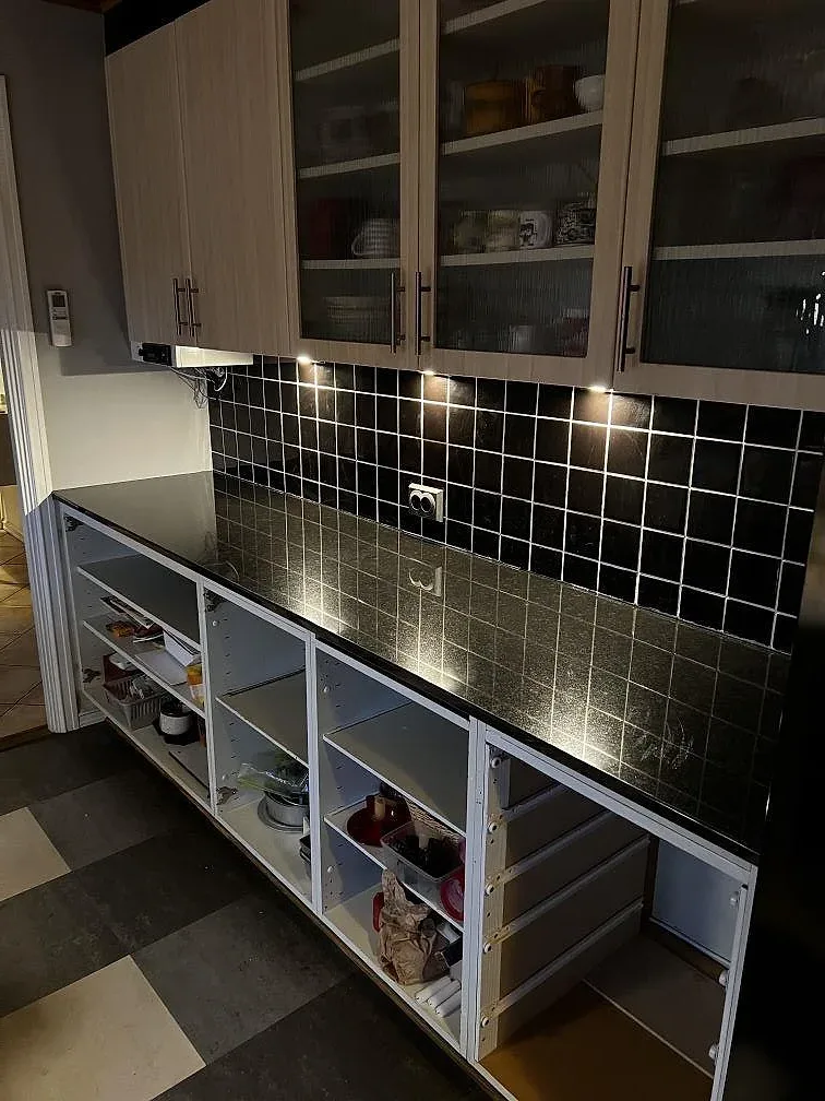 Polerad köksbänkskiva i Nero Assoluto-granit längs köksvägg med glasvitrinskåp i ett kök i Falsterbo.