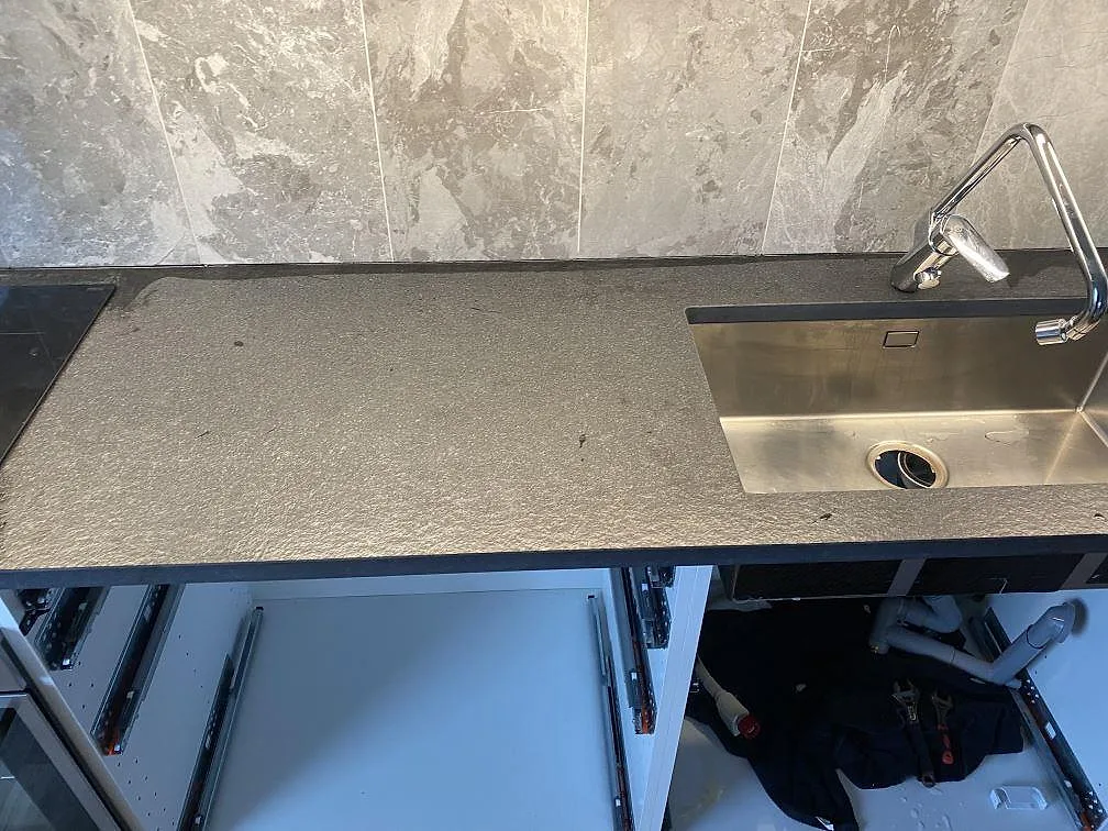 Rak köksbänk i matt Nero Assoluto Flamed and Brushed granit med diskho och öppna stommar i Limhamn.