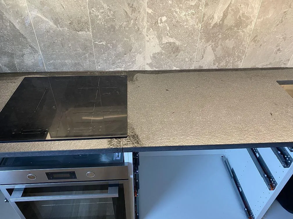 Köksbänkskiva i matt Nero Assoluto Flamed and Brushed granit med svart häll och ugn i Limhamn.