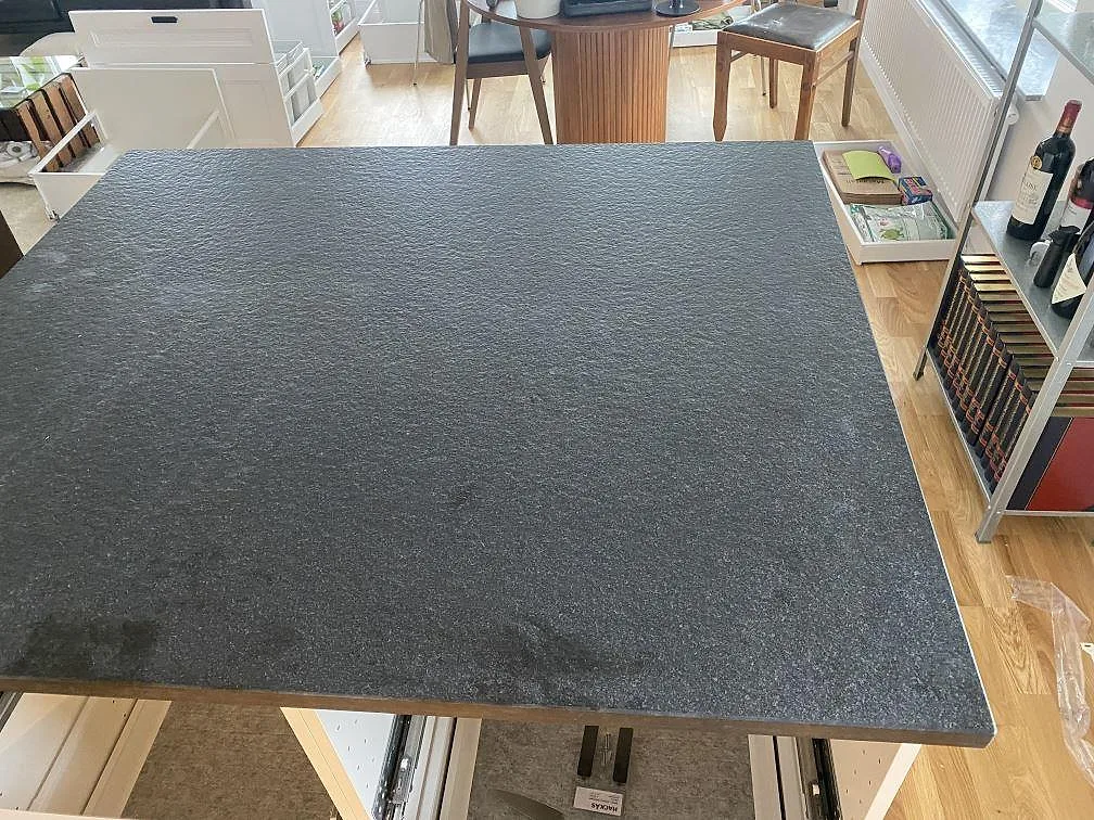 Stor köksö i matt Nero Assoluto Flamed and Brushed granit med tydlig mörk stenstruktur i Limhamn.