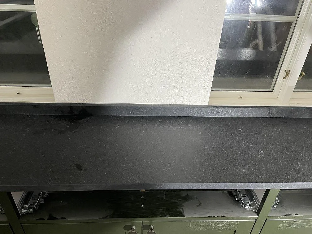 Svart granitbänkskiva i Nero Assoluto Flamed and Brushed med matt struktur över köksstommarna i ett kök i Rydsgaard.