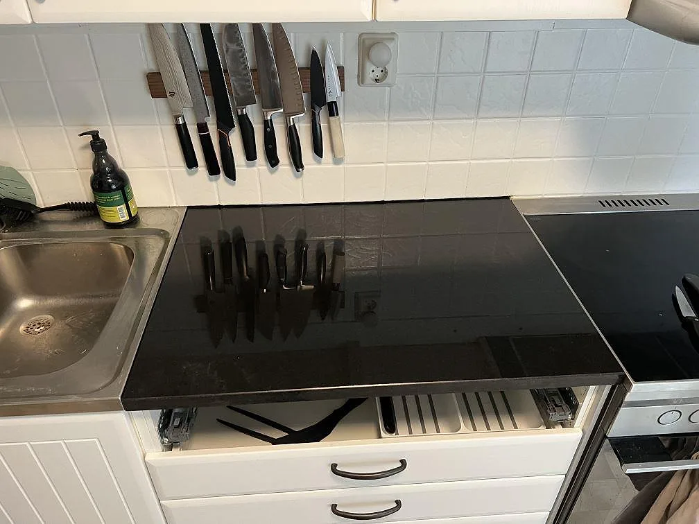 Polerad Nero Assoluto granitbänkskiva mellan diskho och spis i ett kök med vitt kakel i Gnesta.