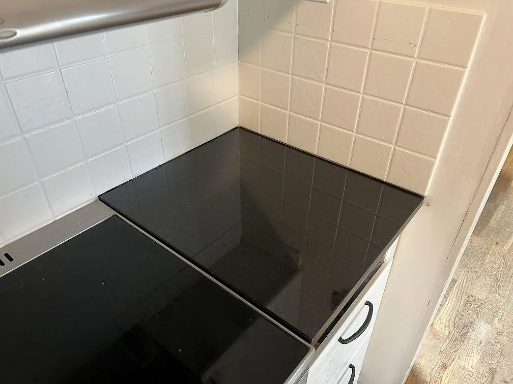Närbild på polerad svart Nero Assoluto granitbänkskiva vid spis och kaklad vägg i ett kök i Gnesta.