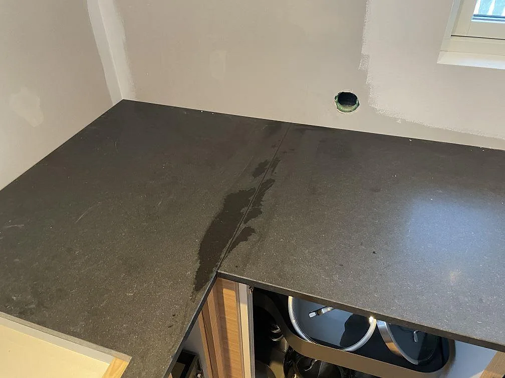 Hörnparti med bänkskiva i matt Nero Assoluto granit och öppna trästommar i Halmstad.