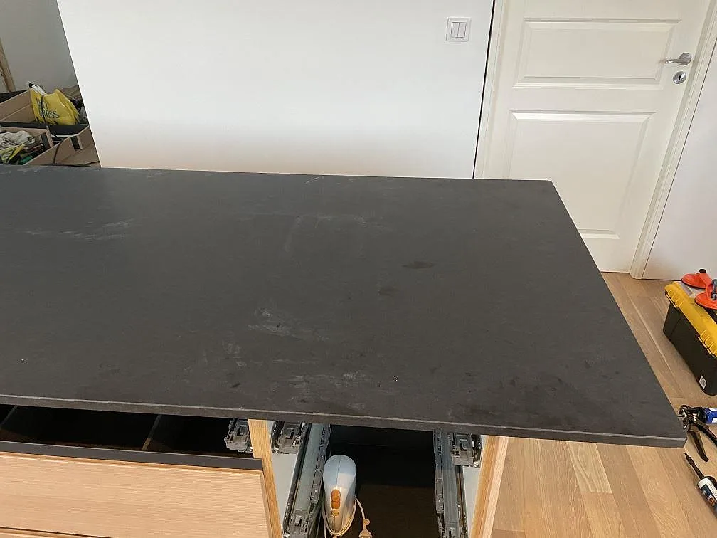 Köksö med bänkskiva i matt Nero Assoluto granit och ljus träinredning i Halmstad.