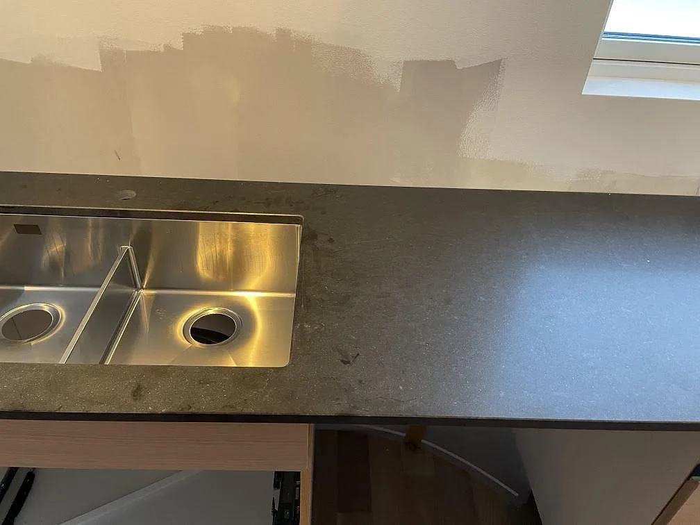 Närbild på matt Nero Assoluto granit med rostfri diskho ovanpå stenen i ett kök i Halmstad.