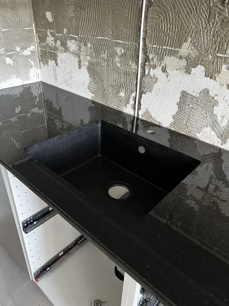 Detalj av underlimmad svart diskho i polerad Nero Assoluto granit med öppna köksstommar i Helsingborg.