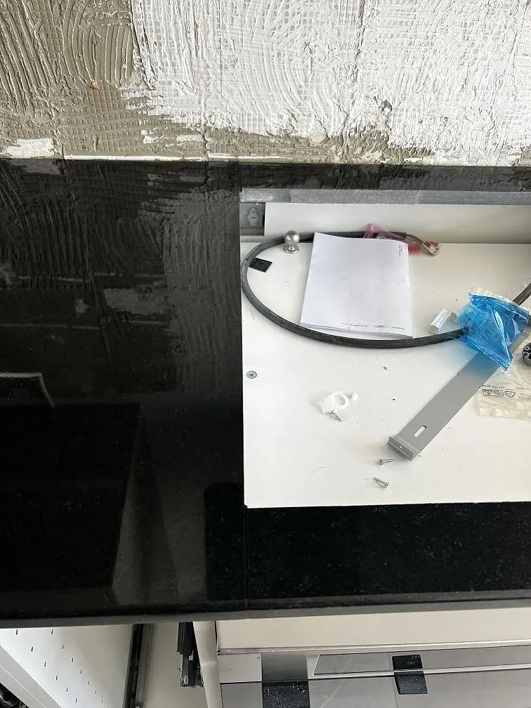 Detaljbild av polerad Nero Assoluto granit runt en öppen köksstomme under montering i Helsingborg.