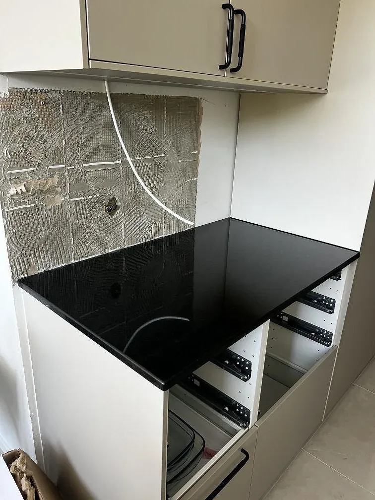 Polerad Nero Assoluto granit på en kökshalvö med vit inredning och svart häll i Helsingborg.