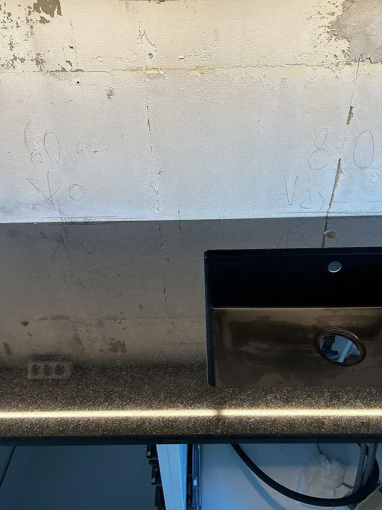 Detalj av underlimmad svart diskho i polerad Nero Assoluto granit med vägg under renovering i Helsingborg.