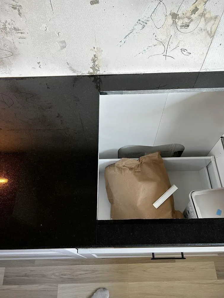 L-formad köksbänkskiva i Nero Assoluto granit, polerad, med öppen stomme och monteringsskede i Helsingborg.
