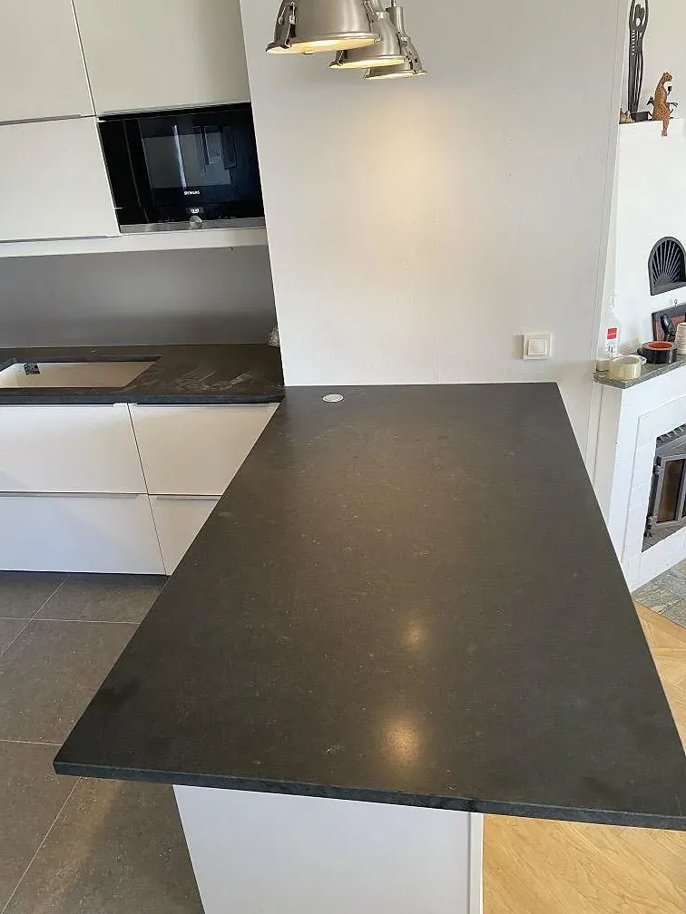 Halvö i svart Nero Assoluto granit mot vita köksskåp och inbyggd ugn i ett kök i Huskvarna, sedd i ögonhöjd under monteringen.
