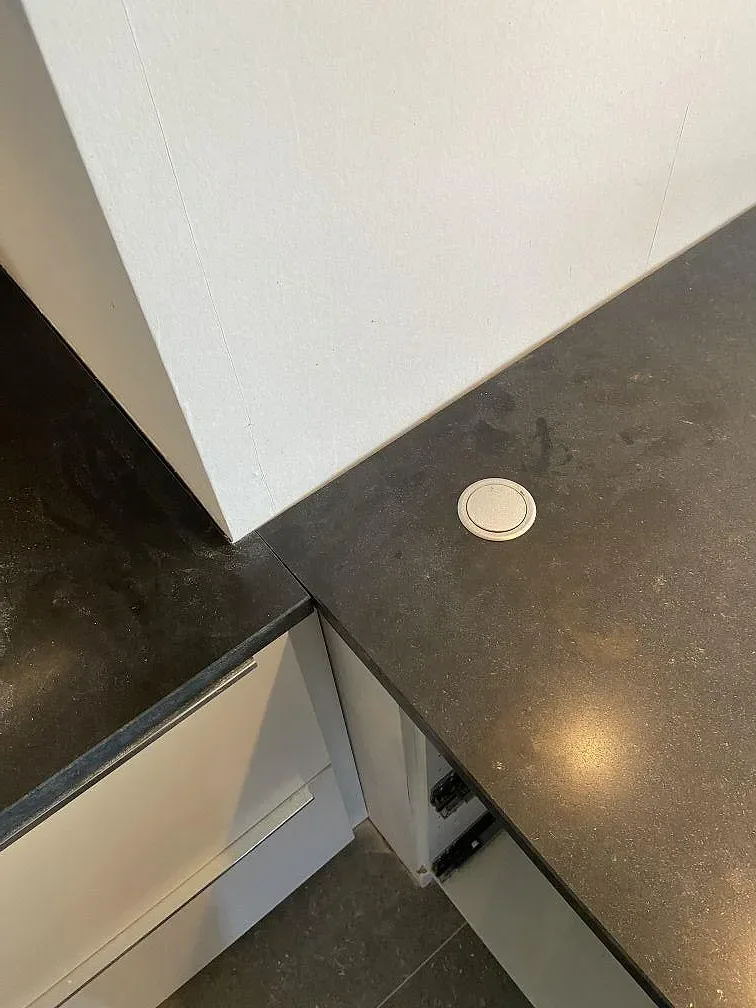 Detalj av svart Nero Assoluto granitbänk med infälld kabelgenomföring i ett kök i Huskvarna.