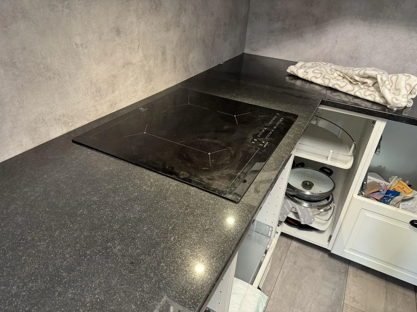 Köksbänkskiva i svart Nero Assoluto granit, polerad, med häll och halvö mot väggar med betonglook i Hyllinge.