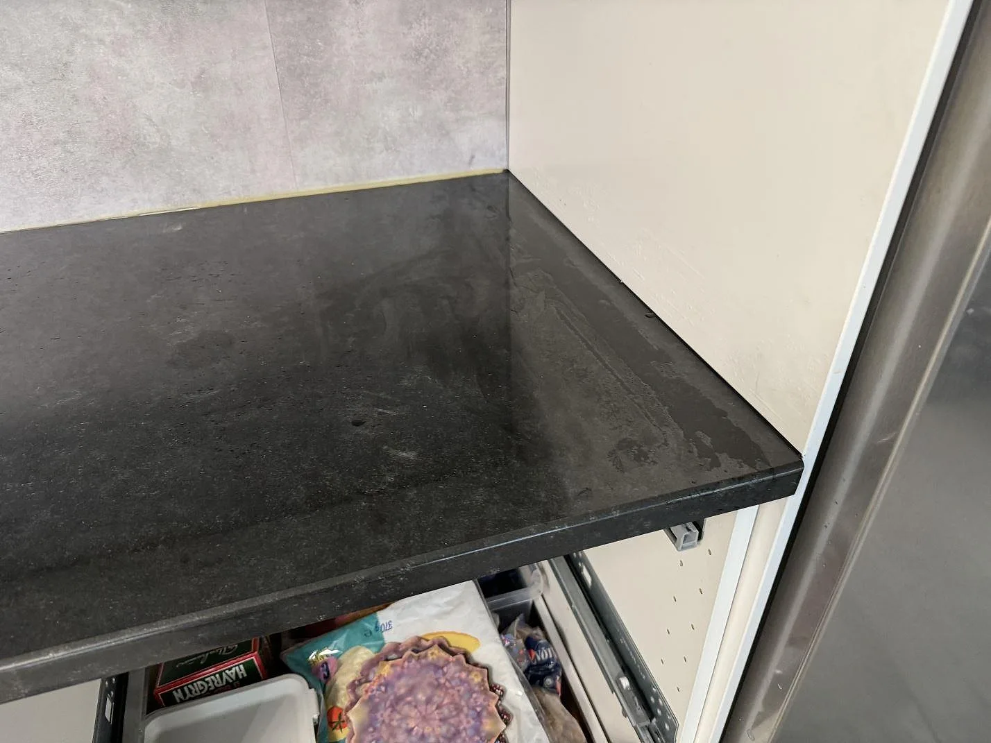 Detalj av 30 mm polerad Nero Assoluto granit vid vägg och högskåp i köket i Hyllinge.
