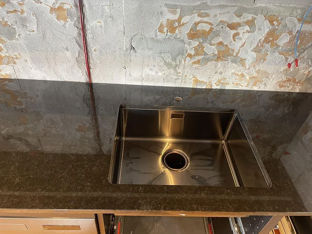 Polerad Nero Assoluto granit med underlimmad rostfri diskho och renoverad väggyta i ett kök i Kävlinge.