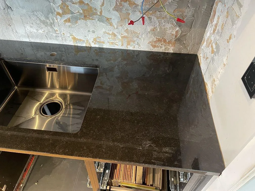 Närbild på köksbänkskiva i polerad Nero Assoluto granit med rostfri underlimmad diskho i Kävlinge.