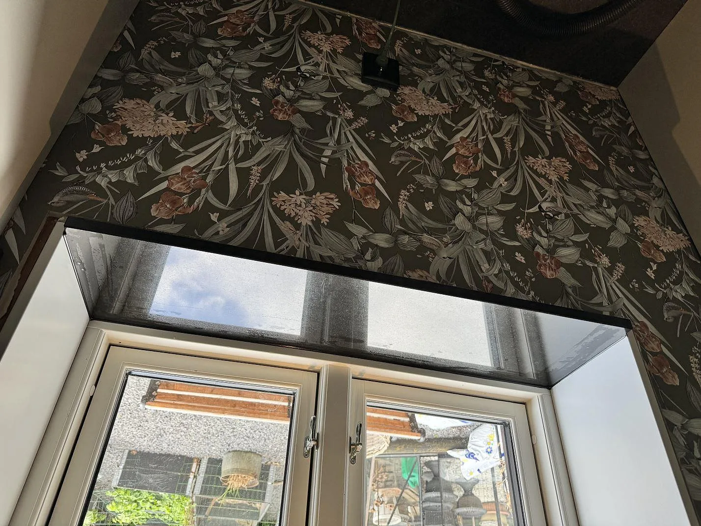 Fönsterbänk i polerad Nero Assoluto granit under floral tapet i Kävlinge.