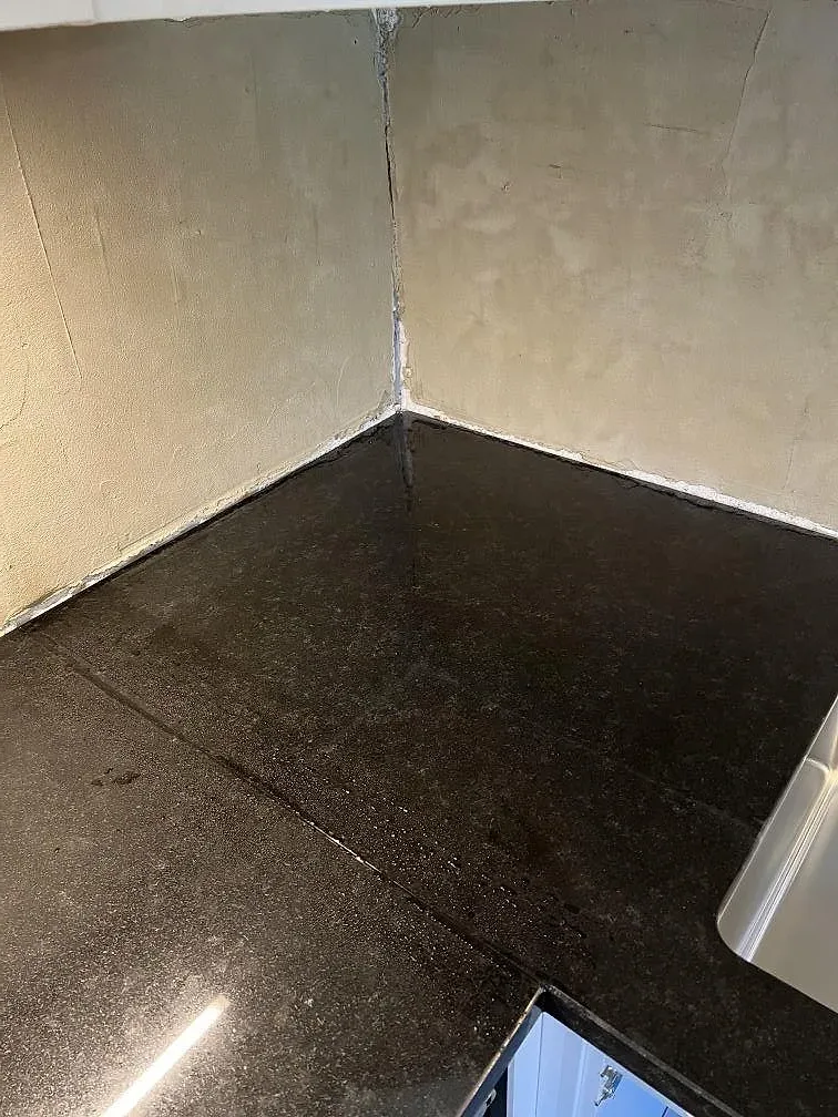 Hörn och skarv i polerad Nero Assoluto granit vid vägg i kök under montering i Kävlinge.