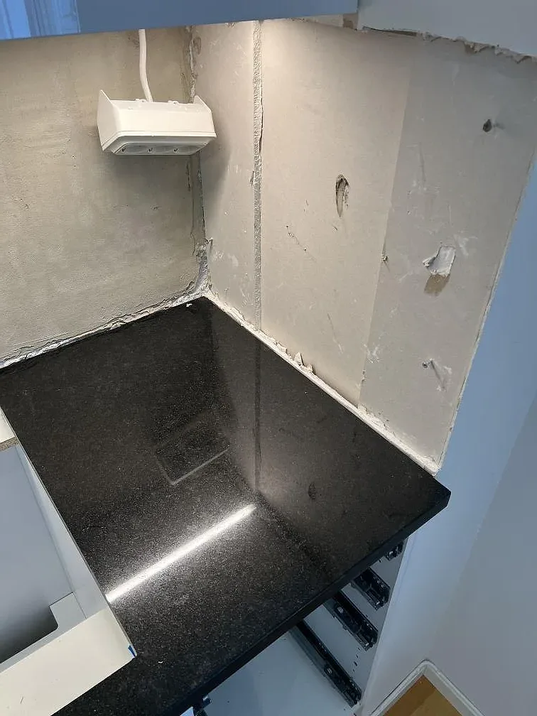 Mörk polerad Nero Assoluto granit med LED-reflex längs vägg och skåpstommar i kök i Kävlinge.