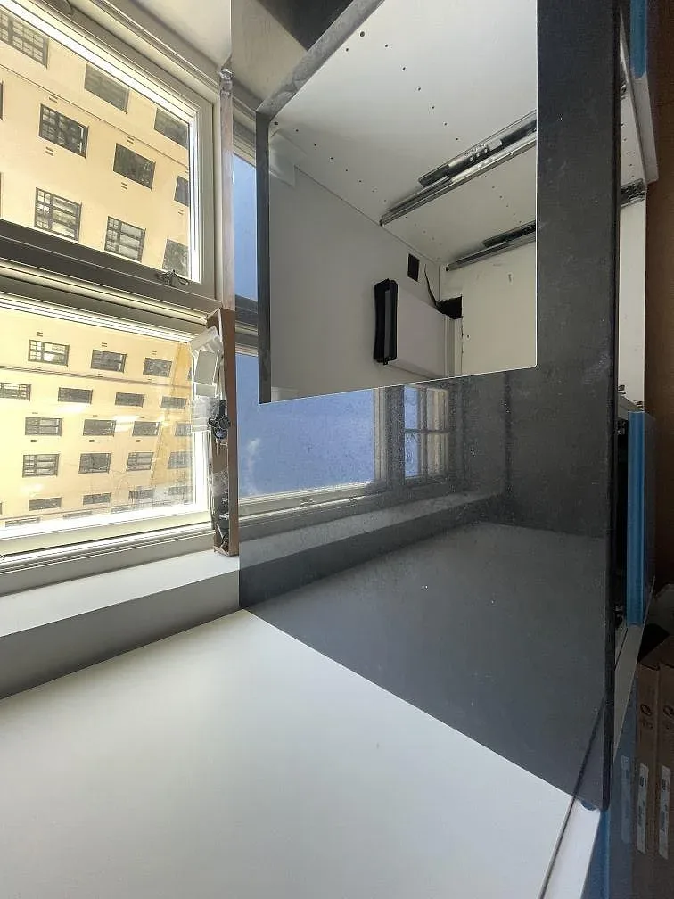 Polerad Nero Assoluto köksbänk i granit längs fönstret med öppen skåpstomme och innergårdsutsikt i en lägenhet i København S.