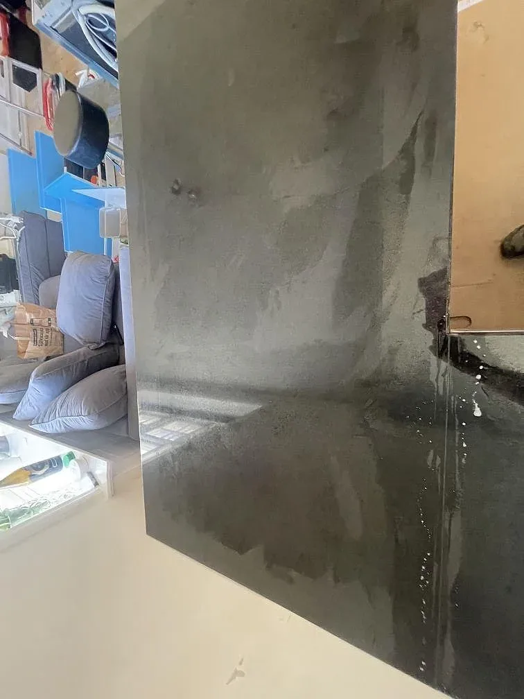 Närbild på underlimmad rostfri diskho i svart Nero Assoluto granit mot bar vägg i ett kök i København S.