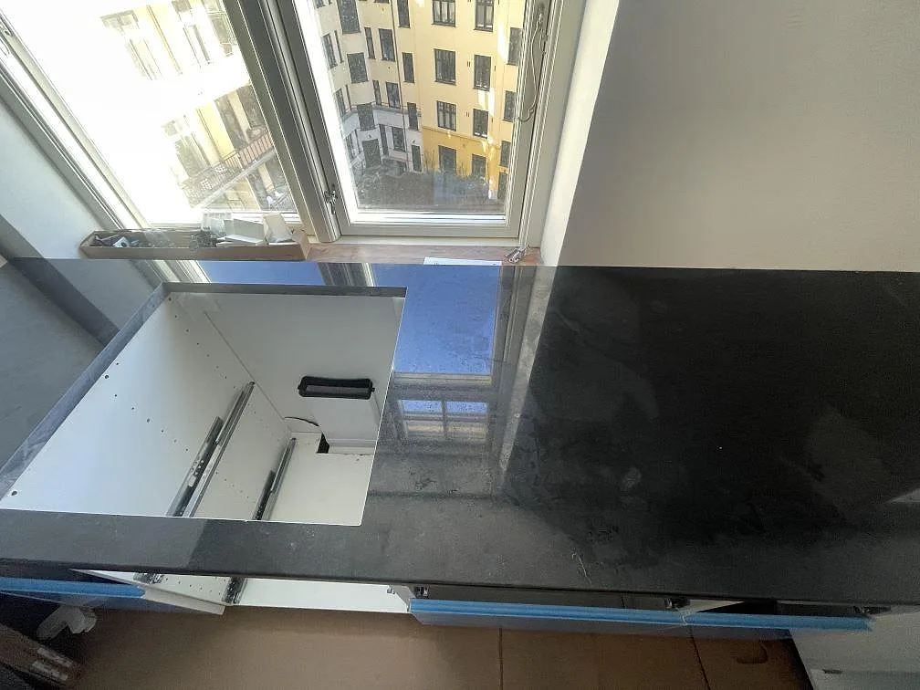 Halvö i polerad svart Nero Assoluto granit som möter köksdelen, fotograferad i ögonhöjd i ett kök i København S.