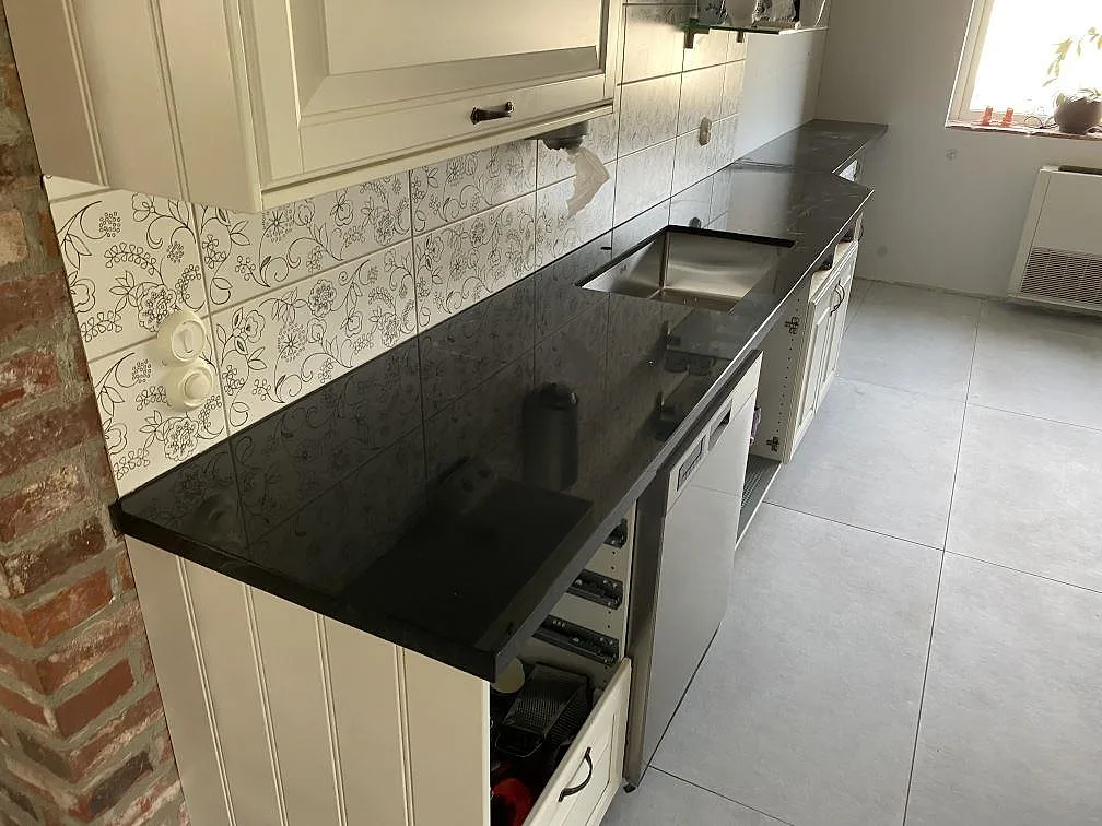 Köksbänkskiva i polerad Nero Assoluto granit, 40 mm, med rostfri diskho i ett kök i Kristianstad.